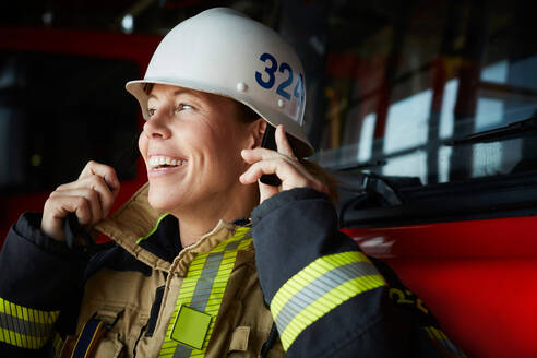 Lächelnde Feuerwehrfrau mit Helm auf der Feuerwache - MASF14207
