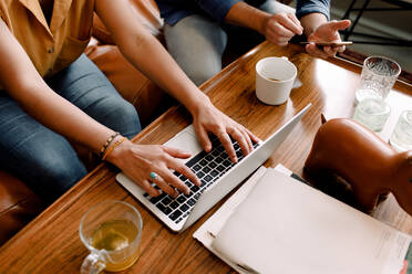 Midsection of female executive typing on laptop while sitting with colleague in office - MASF14215