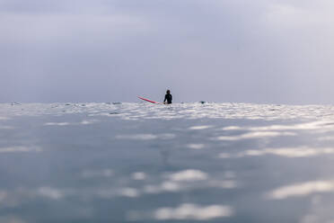 Mid distance view of woman surfing on sea against clear sky - CAVF68351