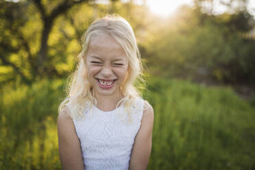 Cheerful girl standing on field in park - CAVF68392