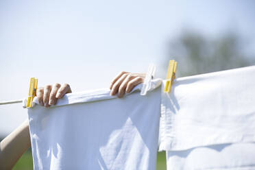 Close-up of woman drying clothes on clothesline - CAVF68454