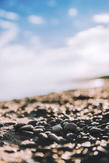 Surface level of pebbles at beach against sky - CAVF68480