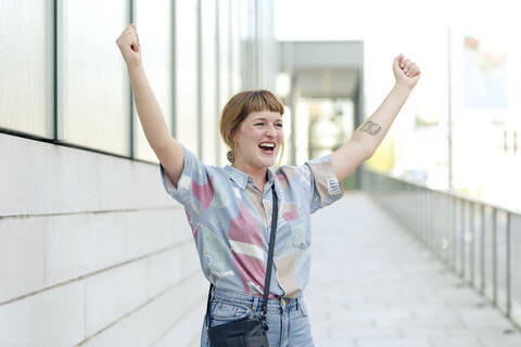 Porträt einer glücklichen jungen Frau, die die Hände hebt, lizenzfreies Stockfoto