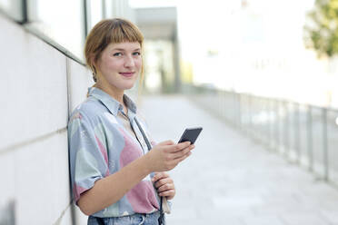 Porträt einer erdbeerblonden jungen Frau mit Mobiltelefon - FLLF00346