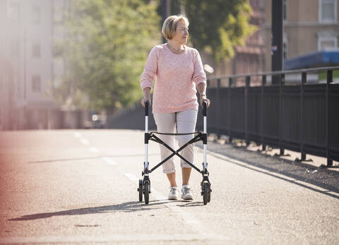 Ältere Frau mit Rollator auf Fußgängerbrücke, lizenzfreies Stockfoto