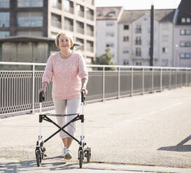 Ältere Frau mit Rollator auf Fußgängerbrücke - UUF19520