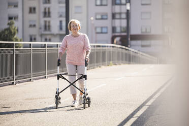 Senior woman with wheeled walker on footbridge - UUF19521