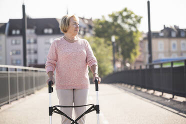 Senior woman with wheeled walker on footbridge - UUF19523