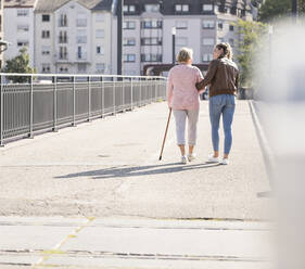 Granddaughter and her grandmother walking on footbridge - UUF19524