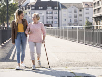 Granddaughter and her grandmother walking on footbridge - UUF19526