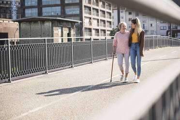 Granddaughter and her grandmother walking on footbridge - UUF19528