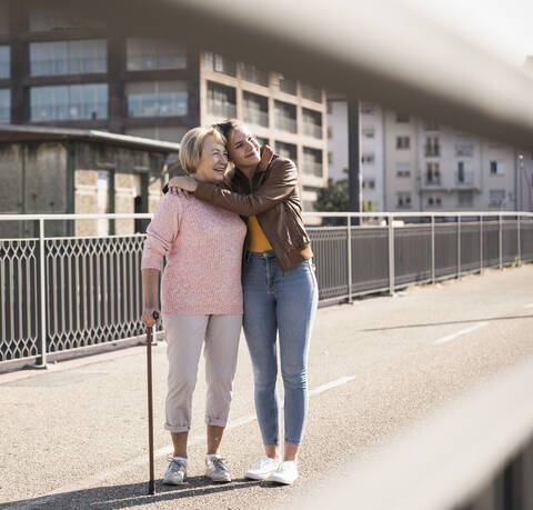 Granddaughter and her grandmother standing on footbridge stock photo