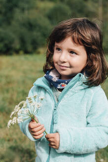 Portrait of smiling little girl with wildflower in autumn - GEMF03275
