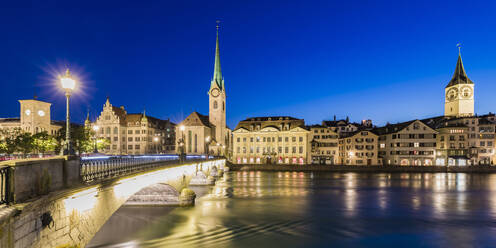 Switzerland, Canton of Zurich, Zurich, River Limmat and old town buildings along illuminated Limmatquai street at dusk - WDF05556