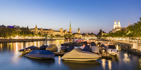 Switzerland, Canton of Zurich, Zurich, Covered boats moored on river Limmat at dusk with old town waterfront in background - WDF05564