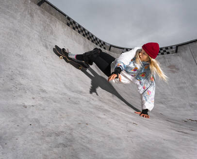 Germany, Baden-Wurttemberg, Waiblingen, Young woman skateboarding in skate park - STSF02344