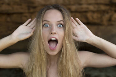 Portrait of screaming young woman raising hands - JPTF00365