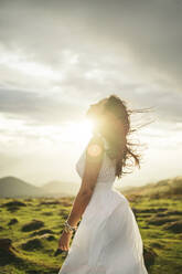 Young woman wearing white dress on viewpoint at sunset - MTBF00165