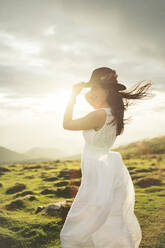 Young woman wearing white dress on viewpoint at sunset - MTBF00166