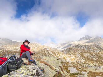 Hiker sitting on a mountain enjoying the view, nature park Adamello, Italy - LAF02409