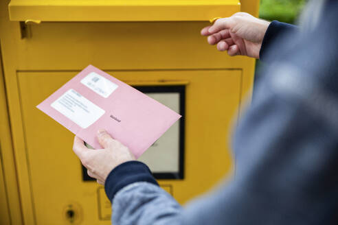 Elector holding documtents for the postal vote in front of the mailbox - MAMF00956