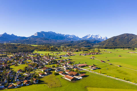 Deutschland, Bayern, Oberbayern, Werdenfelser Land, Krun, Luftaufnahme von grünen Feldern und Dorf mit Wettersteingebirge im Hintergrund, lizenzfreies Stockfoto