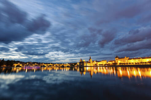 Tschechische Republik, Prag, Skyline der Stadt beleuchtet in der Abenddämmerung über den Fluss gesehen - GIOF07583