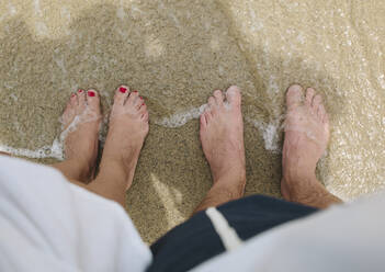USA, California, Santa Monica, Bare feet of man and woman standing side by side on sandy beach - GIOF07609