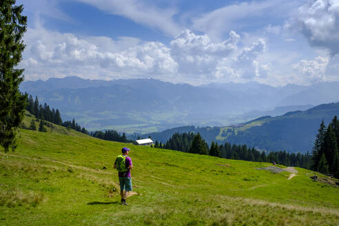 Deutschland, Bayern, Immenstadt, Einsamer Wanderer macht Pause, um die malerische Landschaft der Allgäuer Alpen zu bewundern - LBF02772