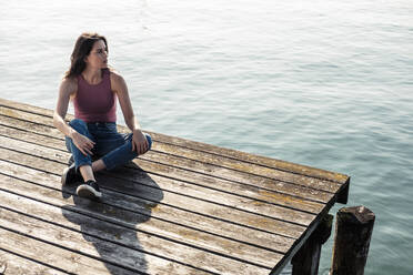 Young woman sitting on jetty looking at distance, Lake Starnberg, Germany - WFF00151