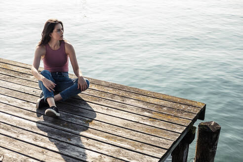 Junge Frau sitzt auf einem Steg und schaut in die Ferne, Starnberger See, Deutschland - WFF00151