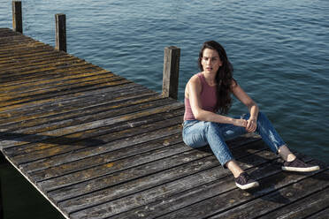Junge Frau sitzt auf einem Steg und schaut in die Ferne, Starnberger See, Deutschland - WFF00152