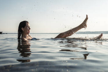 Junge Frau beim Baden im Starnberger See, Spritzen mit Wasser, Deutschland - WFF00159