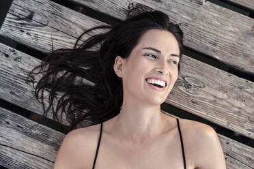 Porträt einer lachenden jungen Frau, die sich auf einem Bootssteg entspannt - WFF00163