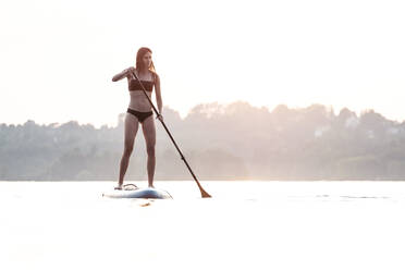 Junge Frau beim Stand-Up-Paddle-Boarding im Sonnenuntergang, Starnberger See, Deutschland - WFF00168