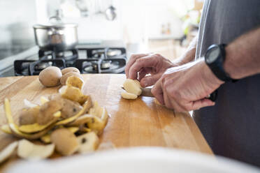 Senior man cutting potatoes on the chopping board - AFVF04165