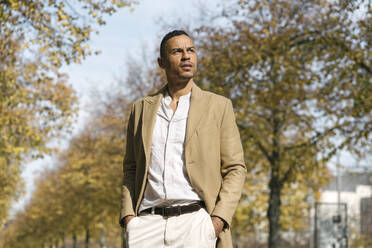 Portrait of pensive businessman standing in the park at autumn - AHSF01072