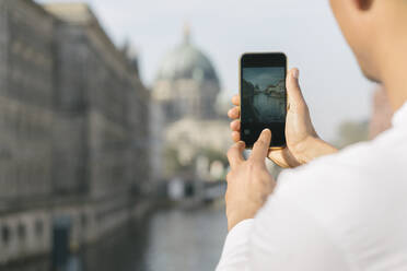 Ausschnittansicht eines Mannes, der mit seinem Smartphone ein Foto vom Stadtzentrum macht, Berlin, Deutschland - AHSF01092