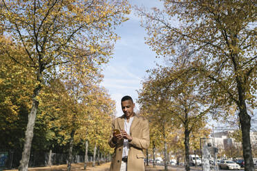 Portrait of businessman using smartphone in autumn - AHSF01113