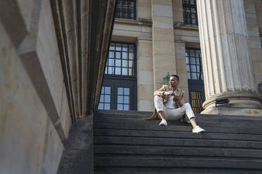 Businessman sitting on stairs with smartphone - AHSF01121