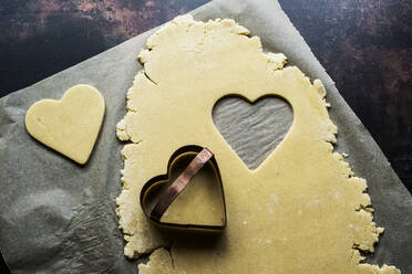 High angle close up of heart-shaped cookies cut out of cookie dough. - MINF12698