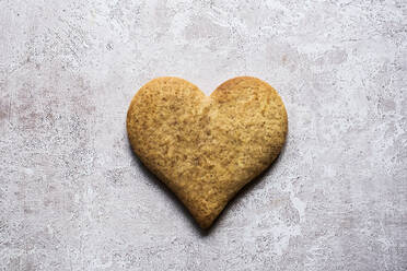 High angle close up of one freshly baked hart-shaped cookie on grey background. - MINF12705