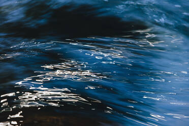 Abstrakte Nahaufnahme von fließendem Flusswasser mit Lichtreflexen auf der Oberfläche. - MINF12733