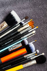 High angle close up of a selection of make-up brushes in various shapes ad sizes. - MINF12751