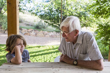 Ein Großvater und sein Enkel sitzen und unterhalten sich. - MINF12770
