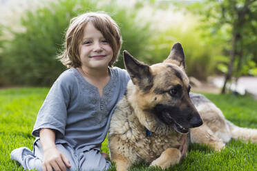 5 year old boy playing with his German Shepherd dog on green lawn - MINF12846