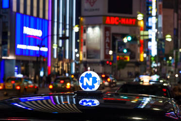 Dach eines Taxis und Leuchtreklamen bei Nacht im Bezirk Shinjuku, Tokio, Japan. - MINF12858