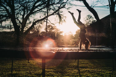 Junges Mädchen auf Trampolin bei Sonnenuntergang - CAVF68497