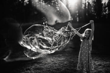 9-jähriges Mädchen macht Riesenseifenblasen in schwarz-weiß - CAVF68501