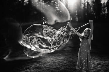 9 year old girl making giant bubbles in black and white - CAVF68501